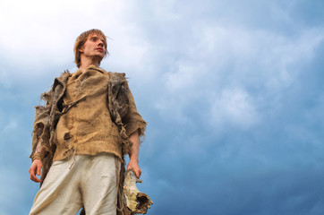 young man in medieval peasant costume on sky background