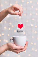 Hands holding a tea bag and cup 