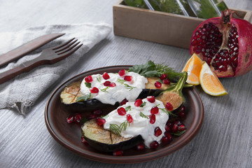 baked eggplants on a plate with cream cheese and pomegranate seeds