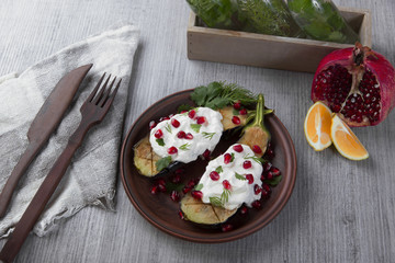 baked eggplants on a plate with cream cheese and pomegranate seeds