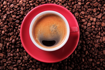 Red coffee cup and saucer one single for espresso or americano on a background of scattered dark coffee beans photo