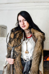 woman with a skin on the shoulders and tongs in hand near a stove