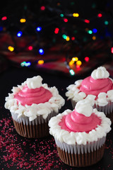 Three Christmas homemade chocolate cupcake with pink cream cheese frosting. Blur light and dark background. Selective focus.