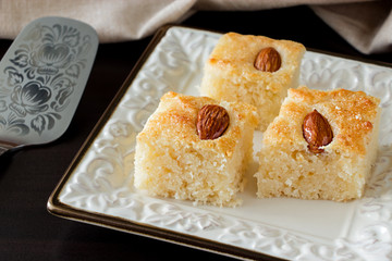 Closeup Three Pieces Basbousa Traditional Arabic Semolina Cake with Almond Nuts Orange Blossom Water. Copy space. Dark background.