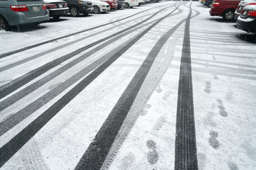 Tire tracks on the street after snow with cars parking on sides