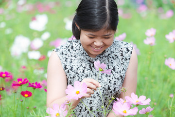 Portrait beautiful happy young girl enjoying smell in a cosmos flowering spring garden © kasipat