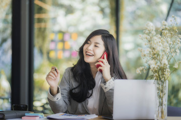 Portrait of an attractive young woman holding her phone while working in coffee shop.