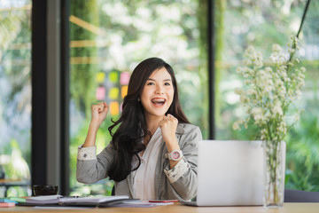 Beautiful Asian girl celebrate with laptop in office.