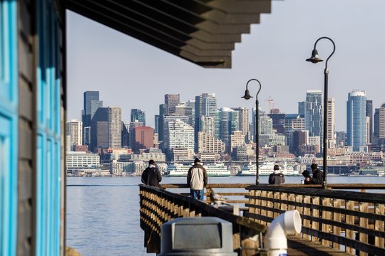 Two people fishing off a dock with the Seattle skyline in the background