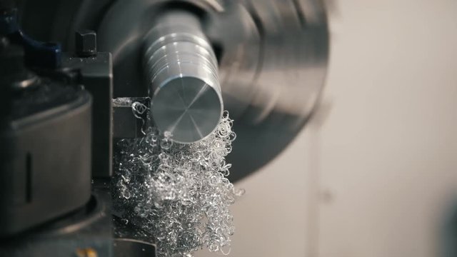Making of metal parts on the lathe machine at the factory, metal shavings, industrial concept, front view
