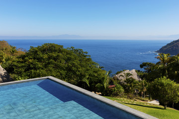 Fototapeta na wymiar Swimming pool overlooking tropical rainforest and the bay of Puerto Vallarta, Mexico