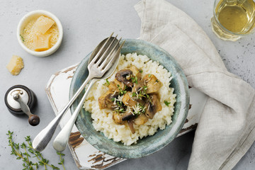 Risotto with chicken and mushrooms, thyme, garlic, parmesan cheese on old gray concrete background. Traditional Italian dish. Selective focus. Rustic style. Top view.