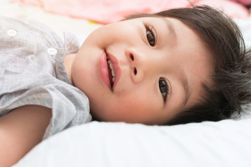Fototapeta na wymiar Cute Little Aisan Boy Smiling on the Couch.
