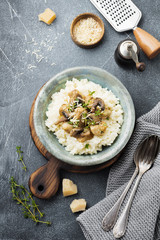 Risotto with chicken and mushrooms, thyme, garlic, parmesan cheese on old gray concrete background. Traditional Italian dish. Selective focus. Rustic style. Top view.