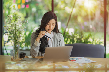 Young woman holding credit card and typing laptop for online shopping