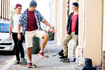 Teenage friends walking at the street with skateboards
