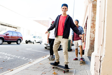 Fototapeta na wymiar Teenage friends walking at the street with skateboards