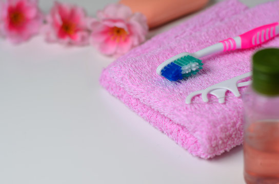 Pink toothbrush and a plastic toothpick on a pink towel