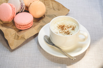Cake macaroon on the plate,cinnamon and a frothy coffee close up