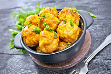 Meatballs in brazier with greens on black board