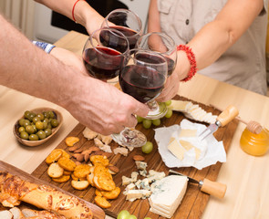 Frends eating cheese with grapes and drinking wine at home together, cheese party concept.