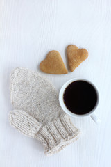 atmosphere with warm feelings/ two gingerbread hearts, warm mitten and mug with coffee on the table top view