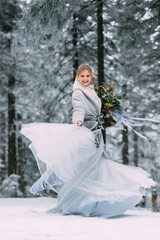 Fototapeta premium The young pretty girl waits for her lover in the middle of the mountains covered with snow