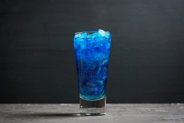 Blue cocktail with cranberry on the wooden background. Selective focus.