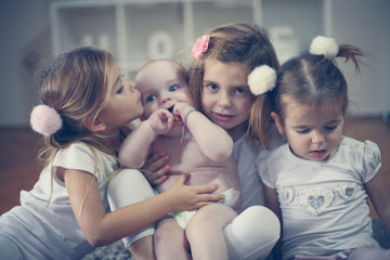 Little baby brother poses to camera with little sisters.