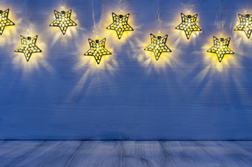 Christmas blank interior with glow lights yellow stars on indigo blue wood background.