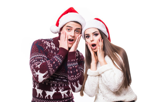 Wow. Portrait of two shocked amased excited lovers in red santa hats