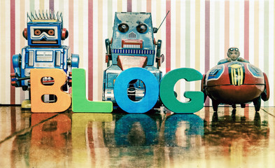 the word BLOG with wooden letters an a retro  robots & rocket toy on a wooden floor with reflection
