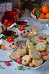 Christmas and new year holiday celebration concept background. Mug of mulled wine with spices, homemade nut cookie, shortbread, xmas tree decoration on wooden table