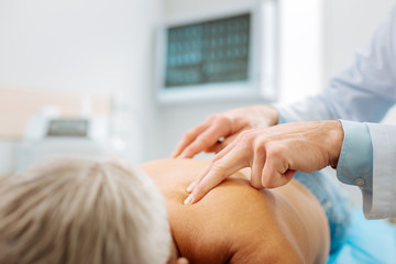 Professional massage. Close up of doctors fingers being pressed to the spine while doing professional massage