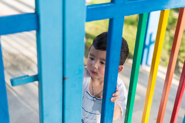 Sad Asian kid behind the grid trying to escape. shallow DOF