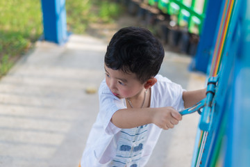 Fototapeta na wymiar Sad Asian kid behind the grid trying to escape. shallow DOF
