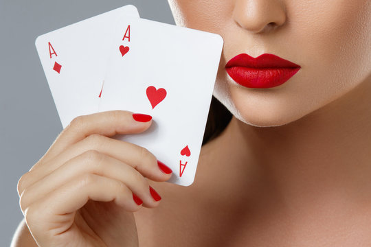 Woman with red lips is holding two aces.