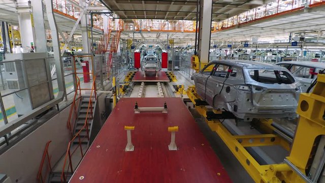 Automobile plant, modern production of cars, car body assembly process, workers serve cars, automated production line. Timelapse.
