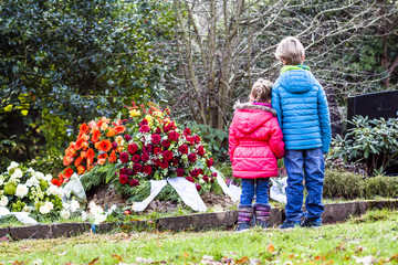 Little brother and sister standing at the grave of their parents