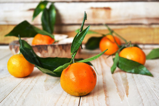 Fresh orange tangerines with green leaves on wooden background. 