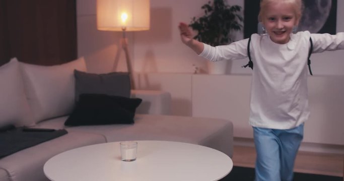 Funny cute dreamer girl wearing rocket pack made from plastic bottles pretending to be an astronaut or pilot. 4K UHD 60 FPS SLO MO