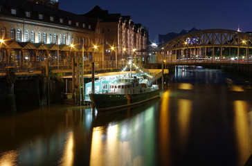 Hamburg Zollkanal mit historischem Zollboot und Brücke im Hintergrund bei Nacht