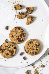 Cookies with dark chocolate chips and remains on white plate.