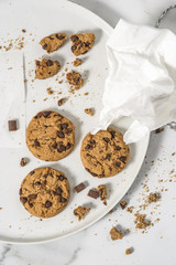Cookies with dark chocolate chips and remains on white plate.