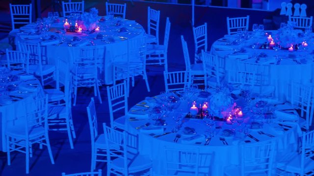 Large round tables decorated in white and prepared for special gala event with important guests.