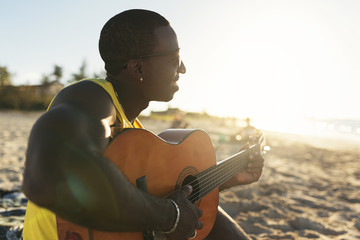 Young cuban man having fun in the beach with his guitar.
