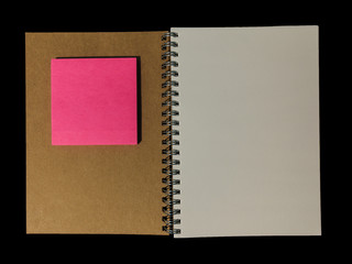Clear color note book opened for note or lecture note or memo for remine and brown cover whit pink color post note or postit in black background.