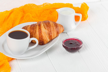Freshly baked croissant orange juice, jam, cup of black coffee on white wooden background. French breakfast. Fresh pastries for morning. Delicious dessert. Closeup photography. Horizontal banner