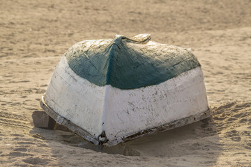 Old wooden boat inverted on the beach