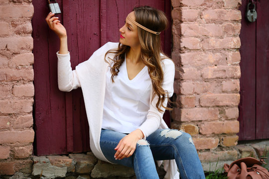 Hippie young tenage woman holding castle wooden door puffy brick background stylish, sitting, fabulous cozy place, wicker handband